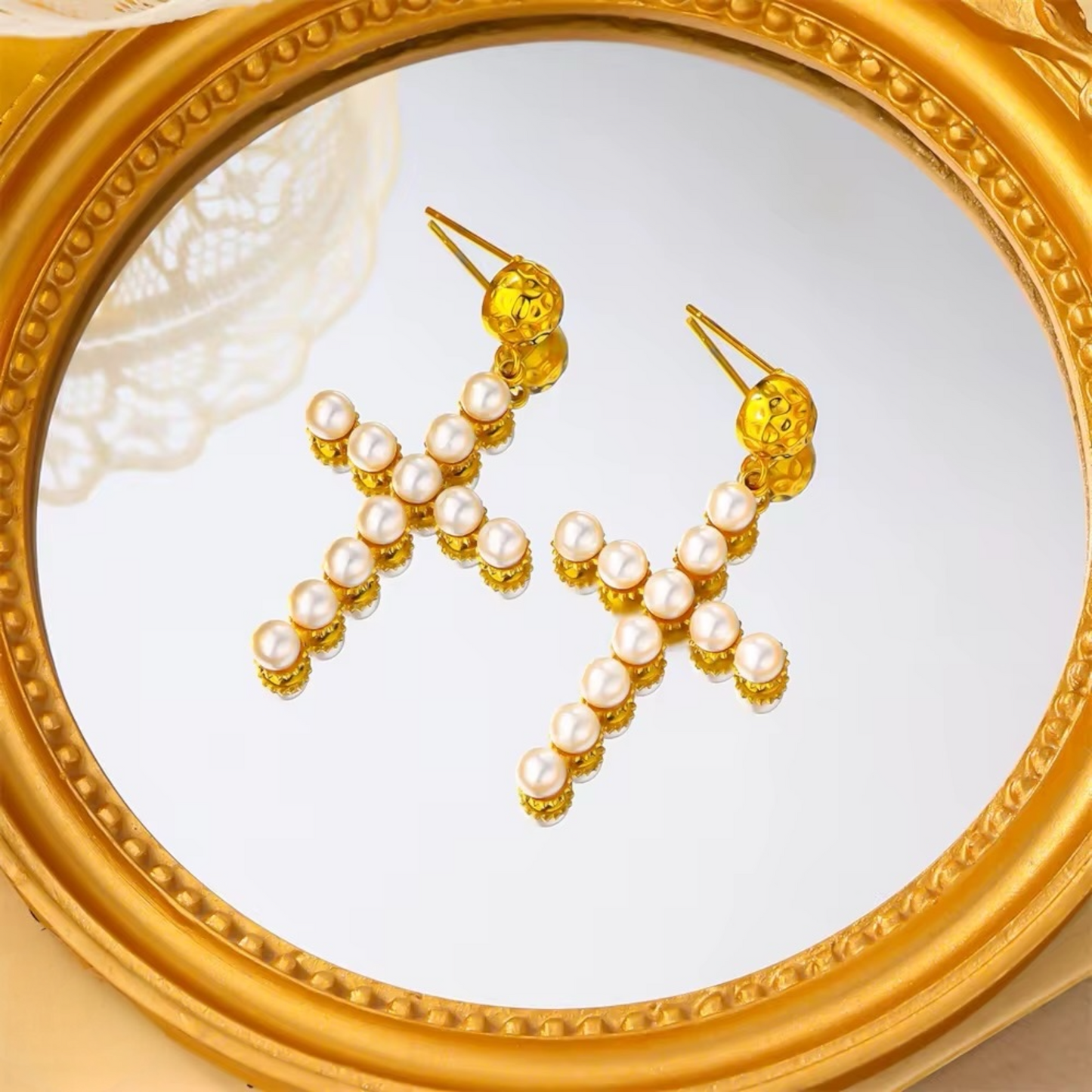 Cross pearl earrings flat lay on white background